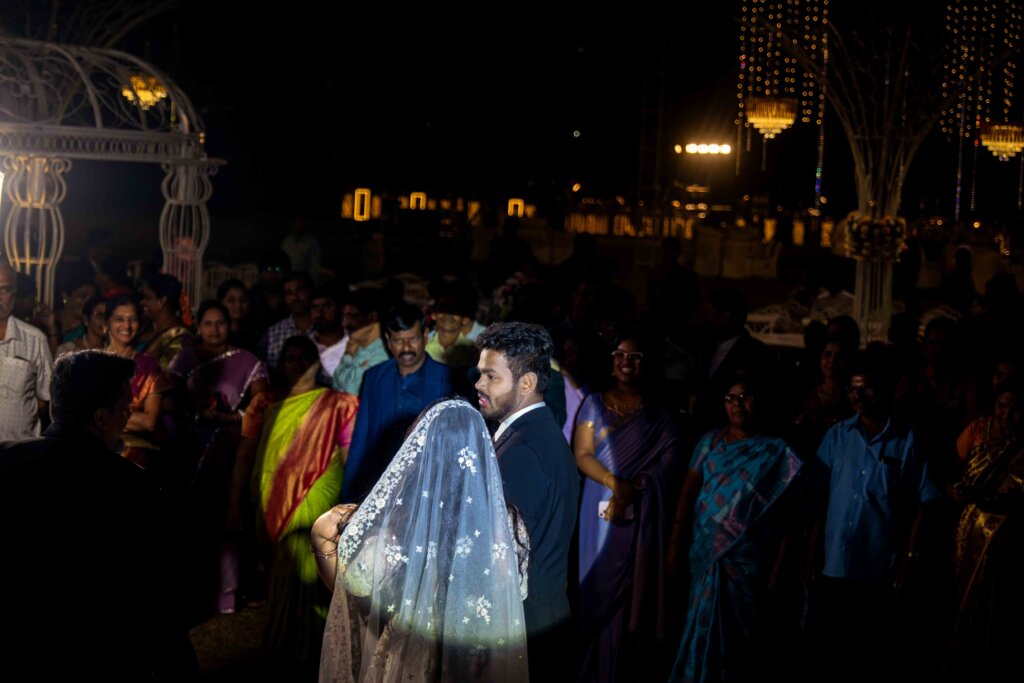 Bride and groom standing under a spotlight at the center of the wedding stage