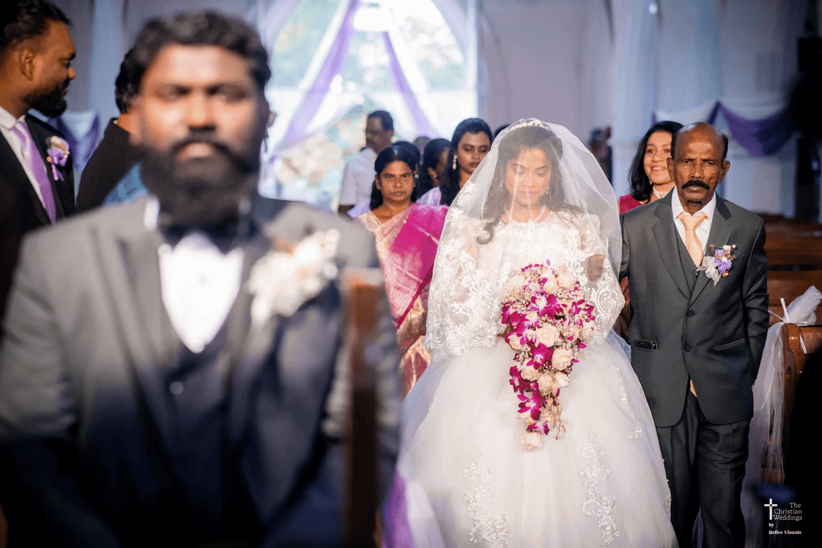 A bride gracefully walks down the aisle, her veil flowing behind her and eyes filled with anticipation.