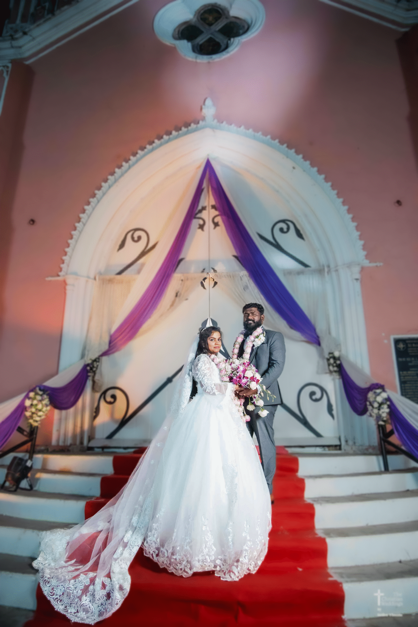 The bride and groom stand hand in hand, smiling happily in front of a beautiful church, ready to begin their married life.