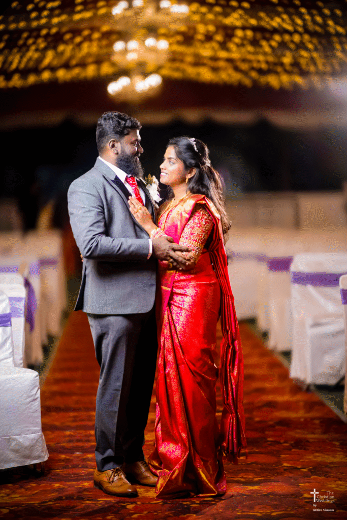 The bride and groom stand together at the reception, smiling and enjoying their special day surrounded by family and friends.