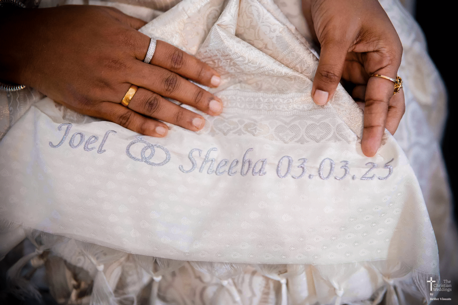 A close-up shot of a traditional silk saree with the couple’s names intricately embroidered in gold thread along the border.