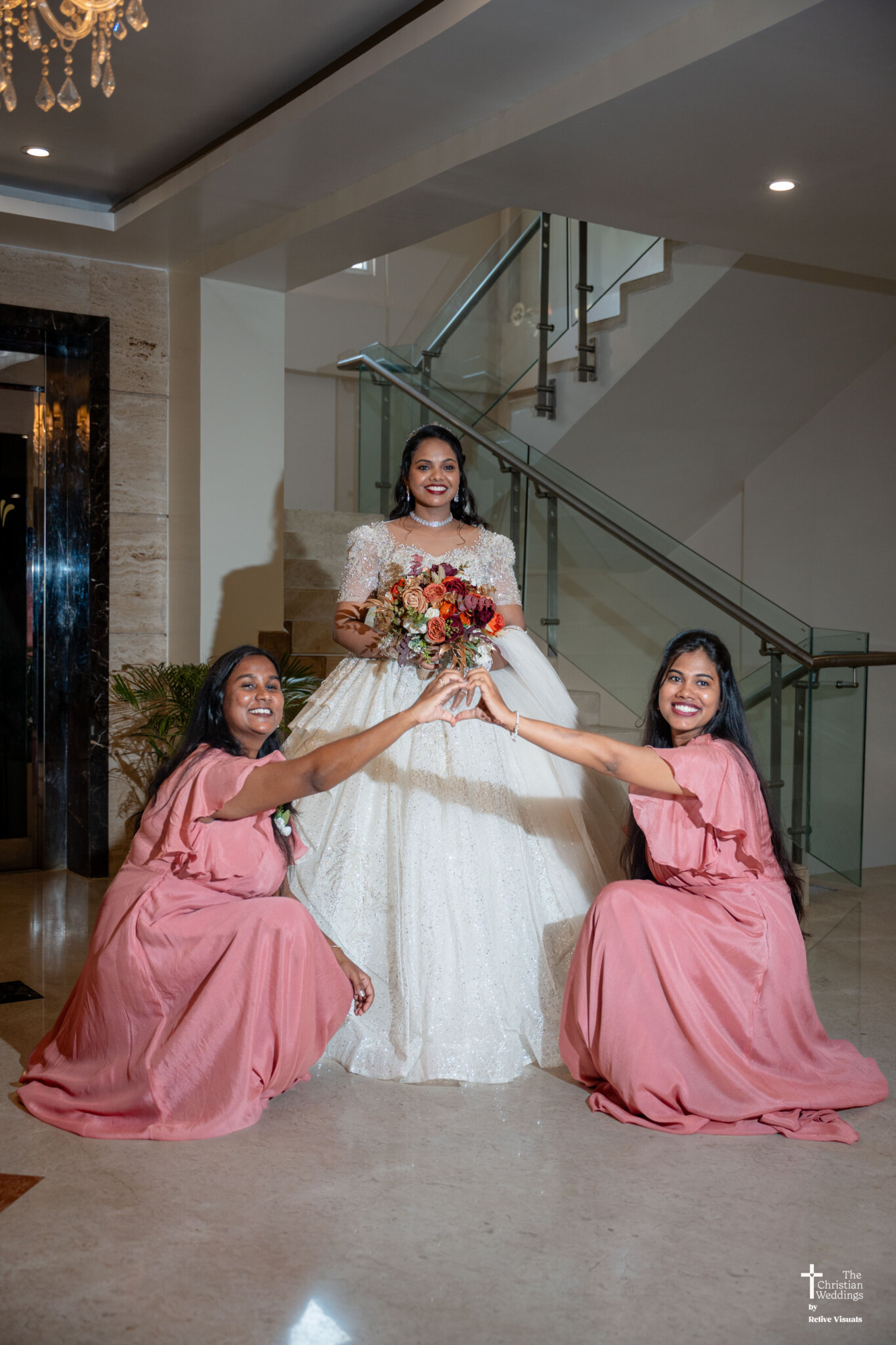 Christian bride holding a flower bouquet while bridesmaids sit around her in a heart formation.