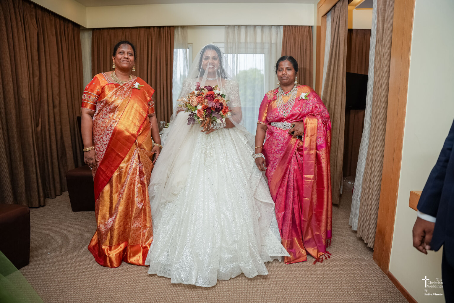 Christian bride standing with her relatives, smiling and surrounded by family members in traditional and modern attire.