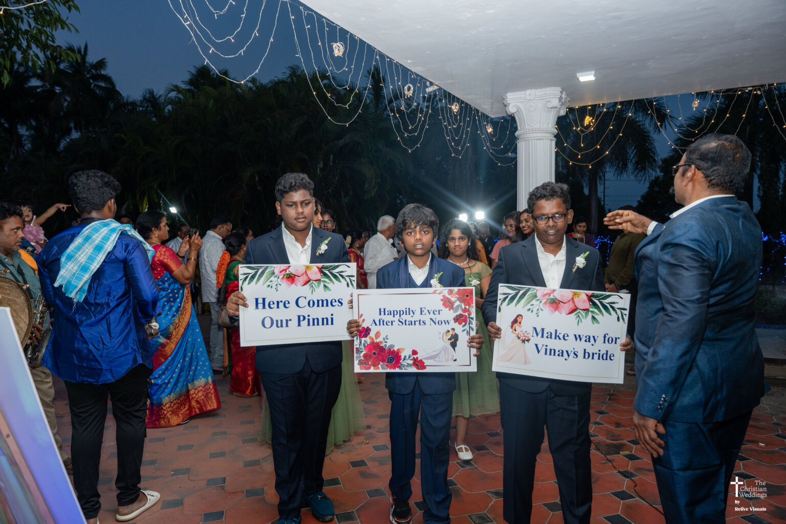 Bride’s cousins holding a colorful signboard welcoming the bride with smiles and excitement.