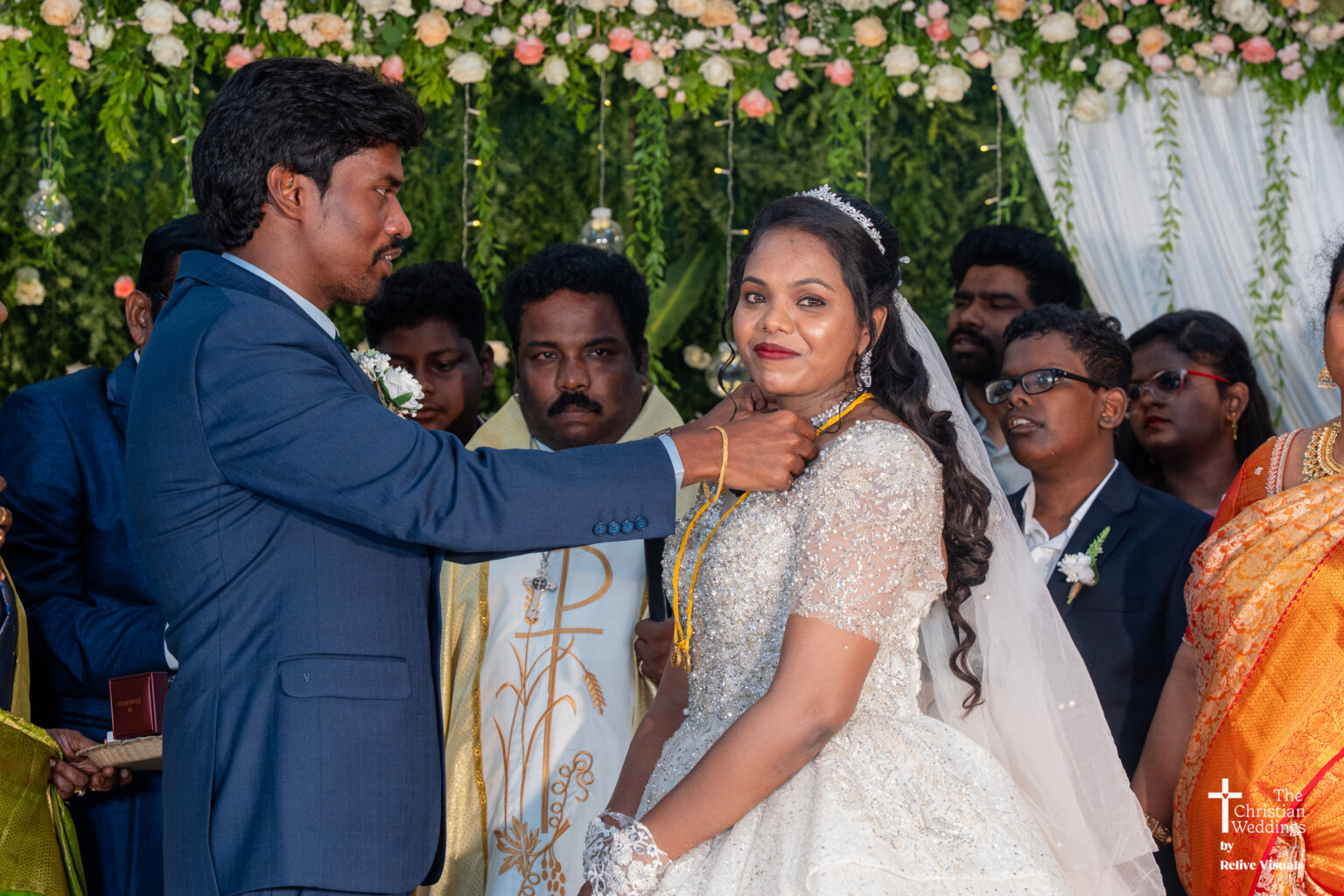 Christian groom tying the thali (wedding necklace) around the bride’s neck during the ceremony.