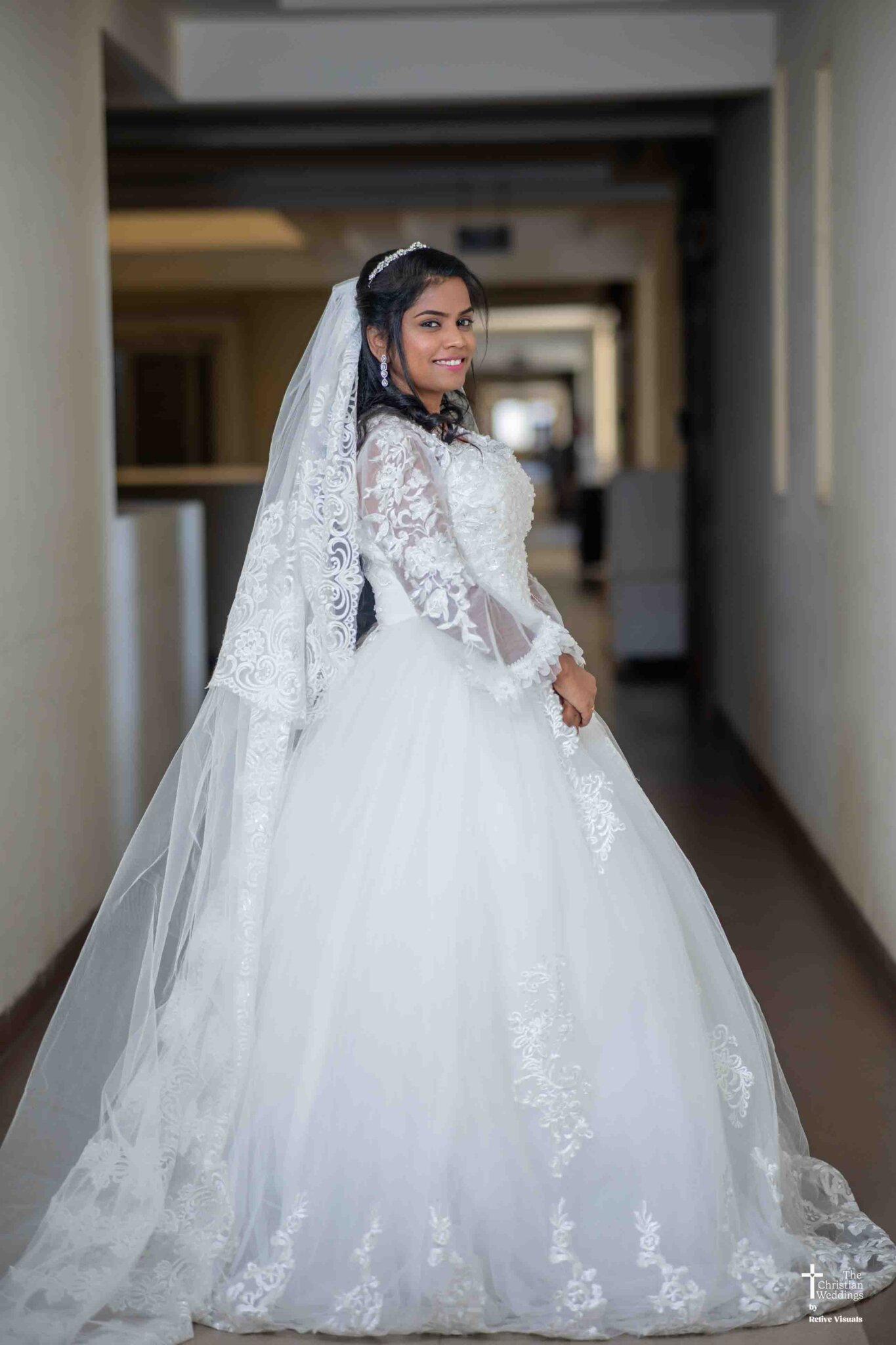A radiant bride stands confidently, posing gracefully for the camera in her elegant wedding attire, her smile glowing with happiness.