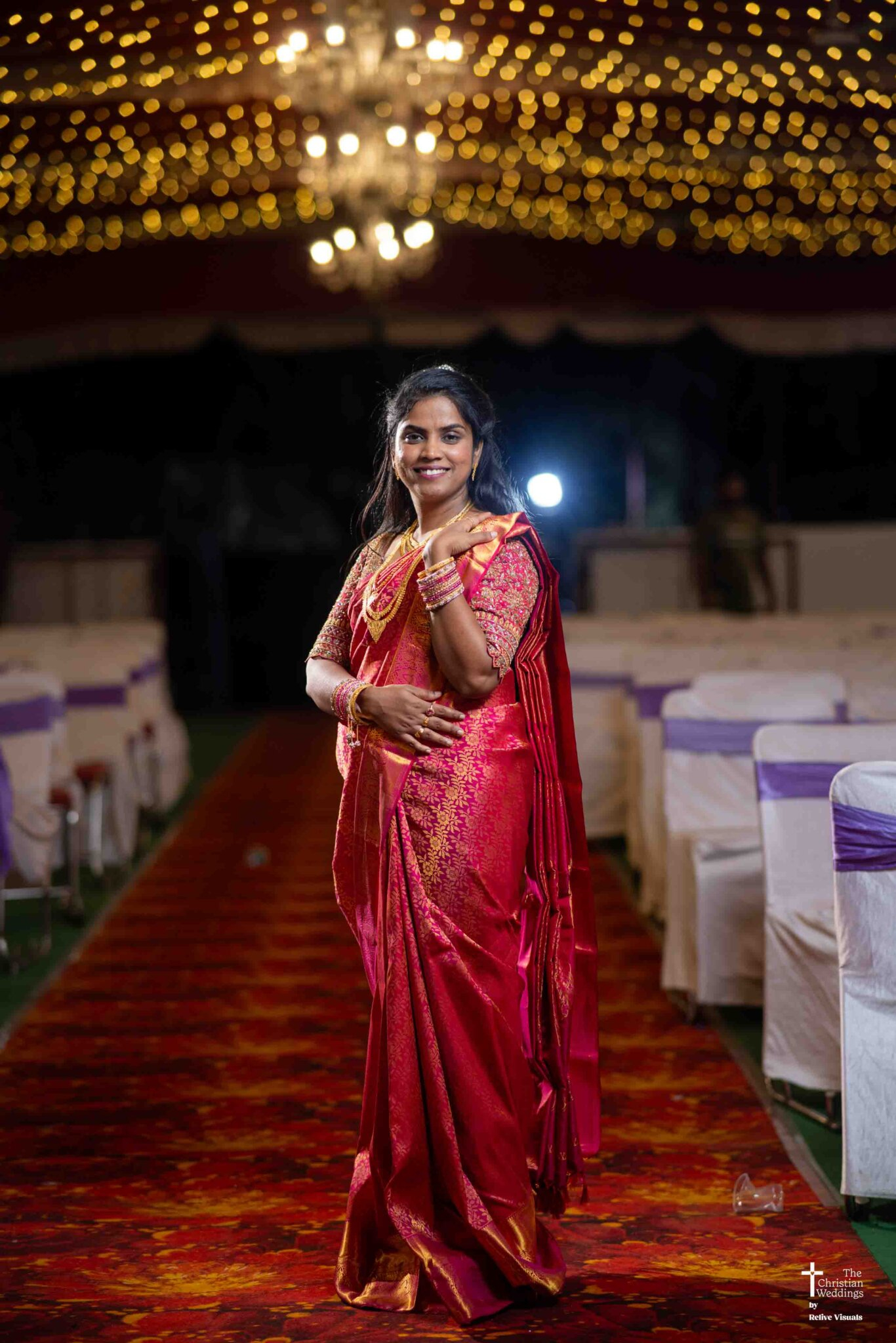 The bride stands gracefully at the wedding reception, glowing in her elegant dress and radiant smile.