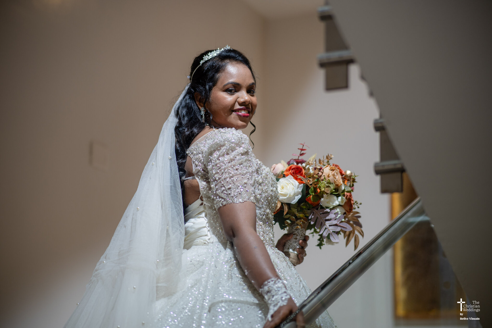 Christian bride in a white gown standing near a church doorway, holding a bouquet and smiling gracefully.